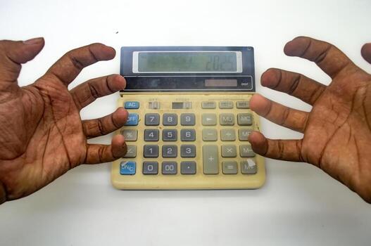 Frustrated hands hovering over a calculator. Concept of financial stress, debt, and mathematical difficulties photo