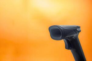 A close up of a black barcode scanner against a vibrant orange background with ample copy space, ideal for retail or technology themes photo