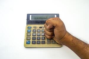 A hand clenched into a fist is placed on an old, dirty calculator, symbolizing frustration or anger with calculations or finances photo