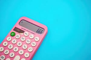 A pink calculator with white buttons displays the number 666 on a blue background, with ample copy space around the image photo