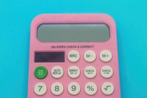A pink calculator with various function keys on a blue background. photo