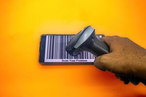 A hand holds a barcode scanner over a smartphone displaying a large barcode with the text Scan Your Problem on an orange background, symbolizing problem solving through technology photo