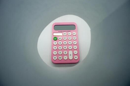 Pink calculator with white buttons on a gray background, featuring various mathematical functions. Ideal for educational or office themed concepts photo