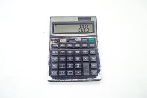 An old, worn out calculator displaying the number 2025 on its screen. The calculator has visible signs of wear and tear, indicating extensive use over time photo