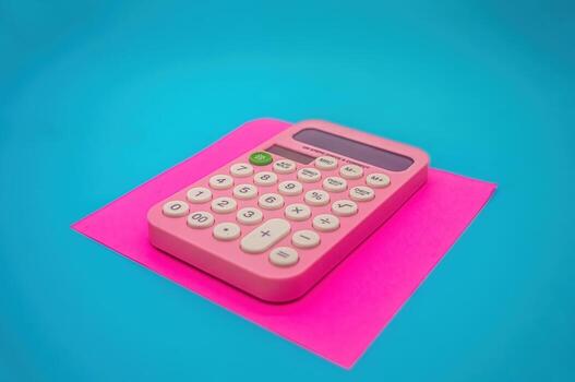 A pink calculator with white buttons is placed on a bright pink sheet against a blue background. The calculator features a green power button and a clear display screen photo