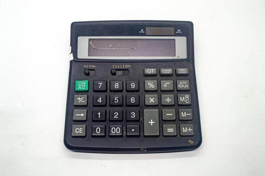 Old, worn out black calculator with a damaged display screen, showing various function buttons and numeric keys, placed on a white background photo