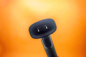 Close up of a barcode scanner against a vibrant orange background. The image highlights the scanner lens and sleek design, making it ideal for retail and inventory management visuals photo
