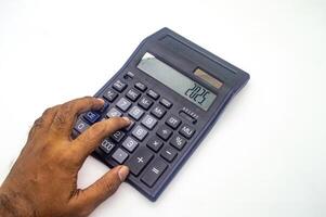 A hand using a calculator with the number 2025 displayed on the screen. The calculator is on a white background photo