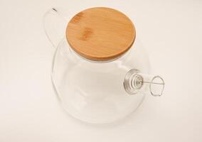Glass teapot with wooden lid on a white background. photo