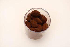 Chocolate-covered almonds in a jar on a white background. photo