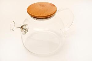 Glass teapot with wooden lid on a white background. photo