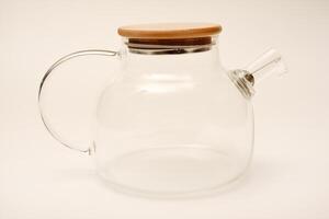 Glass teapot with wooden lid on a white background. photo