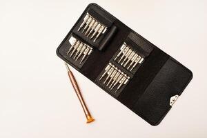 A leather purse with a screwdriver and bits. A set of different screwdrivers. photo