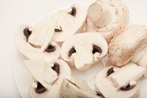 Fresh champignons on a white plate. Mushrooms on a white background. photo