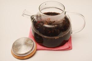 Glass teapot with wooden lid on a white background. A teapot with a teapot inside. photo