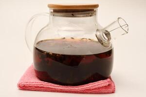 Glass teapot with wooden lid on a white background. A teapot with a teapot inside. photo