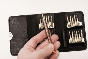 A leather purse with a screwdriver and bits. A set of different screwdrivers. photo