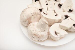 Fresh champignons on a white plate. Mushrooms on a white background. photo