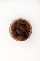 Chocolate-covered almonds in a jar on a white background. photo