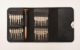 A leather purse with a screwdriver and bits. A set of different screwdrivers. photo