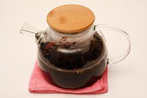 Glass teapot with wooden lid on a white background. A teapot with a teapot inside. photo