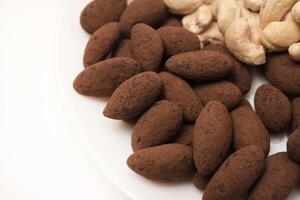 Cashews and hazelnuts almonds in cocoa in a jar on a white background. Nuts on a plate. photo