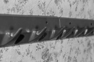 Closet organizer with hooks mounted on a floral patterned background in a home setting photo
