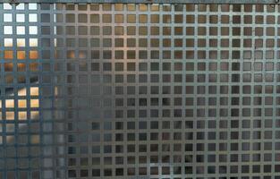 Metallic grid pattern creating intricate shadows at sunset in an urban environment photo