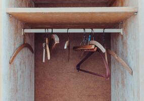 Wooden hangers hang in an empty wardrobe with some signs of wear and rustic charm showcasing their utility and design photo
