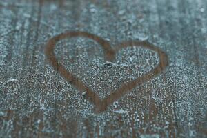 Heart shape etched into a wooden surface covered in a fine layer of dust during a quiet afternoon photo