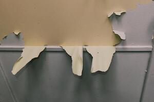 Torn wall paint revealing underlying layers in an indoor setting during daylight hours photo