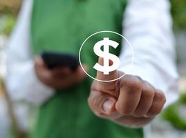 American Dollar sign in front of the index finger of a man holding a cell phone. photo