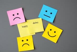 Four colorful sticky notes with happy, sad, and sad faces photo