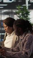 Vertical African american businesswomen collaborating on monthly revenue balance calculation, strategizing a plan for enterprise development. Team of executive staff evaluating analytics on pc. Camera B. video