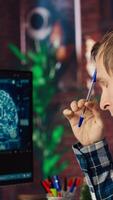 Admin uses computer for artificial intelligence computing simulation, waiting for code to finish compiling. Man works with AI deep neural networks, rubbing forehead with pen, feeling bored, camera B video
