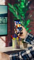 Man at home having fun looking at social media reels done by online content creators. Employee taking break from work to use mobile social network app, screensaver activating on PC, camera B video