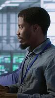 Vertical Data center software developer maintaining company network infrastructure by configuring and troubleshooting hardware. Close up of woman in server hub ensuring optimal system performance, camera A video