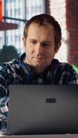 Freelancer in home office sitting at desk, excited after having success with project online, looking at laptop screen. Man celebrating after receiving good news, looking at notebook screen, camera B video