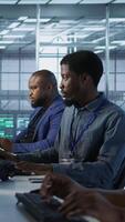 Vertical African american data center technicians implement AI predictive maintenance systems. Woman in server hub using artificial intelligence to identify hardware failures, camera A video