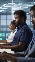 Vertical Server room engineers panicking after seeing disaster recovery plans fail, unable to avoid downtime. Stressed data center workers frightened after seeing performance drop while monitoring it, camera A video
