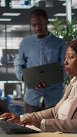 Vertical African american team members engaged in administrative tasks with archived files, reviewing data reports and corporate analytics to ensure alignment with enterprise goals for success. Camera B. video