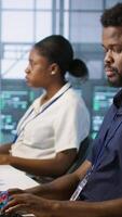 Vertical Server room engineers panicking after seeing disaster recovery plans fail, unable to avoid downtime. Stressed data center workers frightened after seeing performance drop while monitoring it, camera A video