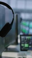 Vertical Close up of headphones left by worker on server room PCs used by employees working to ensure minimal downtime. Equipment in data center workplace used for monitoring performance video