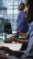 Vertical Programmer seeing red critical error popup on computer display in data center, panicking. African american man in server hub spamming keyboard buttons after receiving error, camera A video