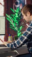 Man in home office looking at UI on PC screen, typing and executing programming code. Coding application UI used by IT developer writing and testing code in modern workspace, camera B video