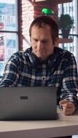 Freelancer in home office sitting at desk, excited after having success with project online, looking at laptop screen. Man celebrating after receiving good news, looking at notebook screen, camera A video