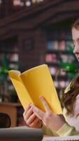 Vertical Teenager immersed in reading literary works from the school library database, focusing on her education and preparing for mandatory assignments or lectures. Diligent girl loves to read. Camera B. video