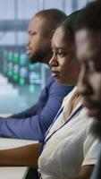 Vertical Software developers in data center implementing AI predictive maintenance systems. Focus on man in server hub office using artificial intelligence to identify hardware failures, camera A video