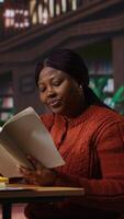 Vertical African american professor preparing her learning materials and resources in the library, leveraging expertise to mentor scholars and create a productive academic atmosphere for pupils. Camera B. video