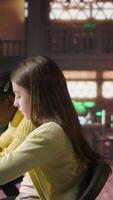 Vertical Preteen girls focus on reading the required books at a study desk, developing their academic skills and literary language at the library. Scholars enjoy lecture for the school curriculum. Camera A. video
